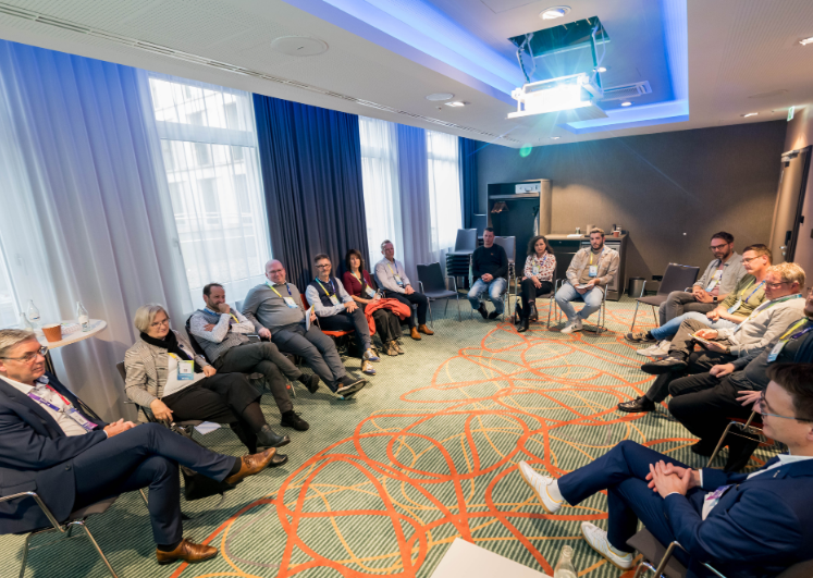 Workshop im Konferenzraum: Teilnehmende sitzen im Stuhlkreis und diskutieren